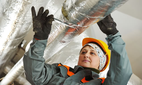 Woman reaching up to repair insulated pipe
