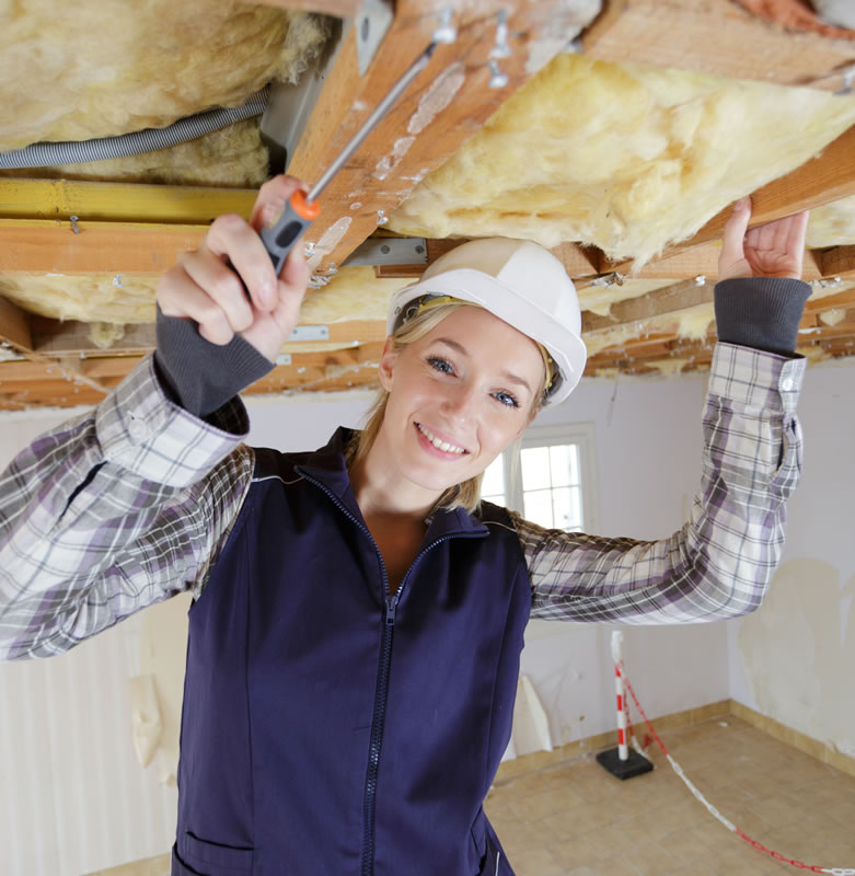 Woman reacing up to roof insulation smiling at the camera